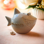 Sparschwein Weiß mit goldenen Details, Aufschrift in Gold: Hai-Raten, romantischer Hintergund in Rosa und Gold mit Blumen 