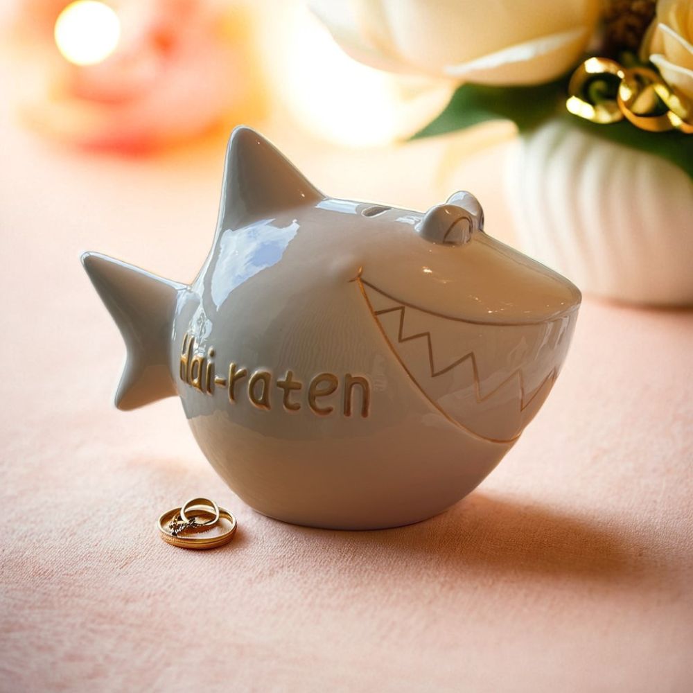Sparschwein Weiß mit goldenen Details, Aufschrift in Gold: Hai-Raten, romantischer Hintergund in Rosa und Gold mit Blumen 