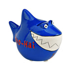 Dunkelblauer Hai, Sparschwein aus Keramik in Hai Form mit Hai Flossen, großes Weißes Gebiss, lustige 3D Augen, rote 3D Aufschrift auf der Seite: Immo-Hai, schräg von der linken Seite fotografiert, rote Kravatte