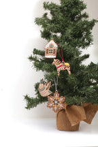 Die bestickten Holz Schmuckstücke hängen an einem Tannenbaum