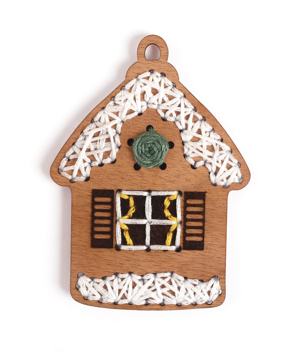 Nahaufnahme des Holz Lebkuchenhaus Schmuckstücks bestickt mit gelbem grünem und weißem Garn