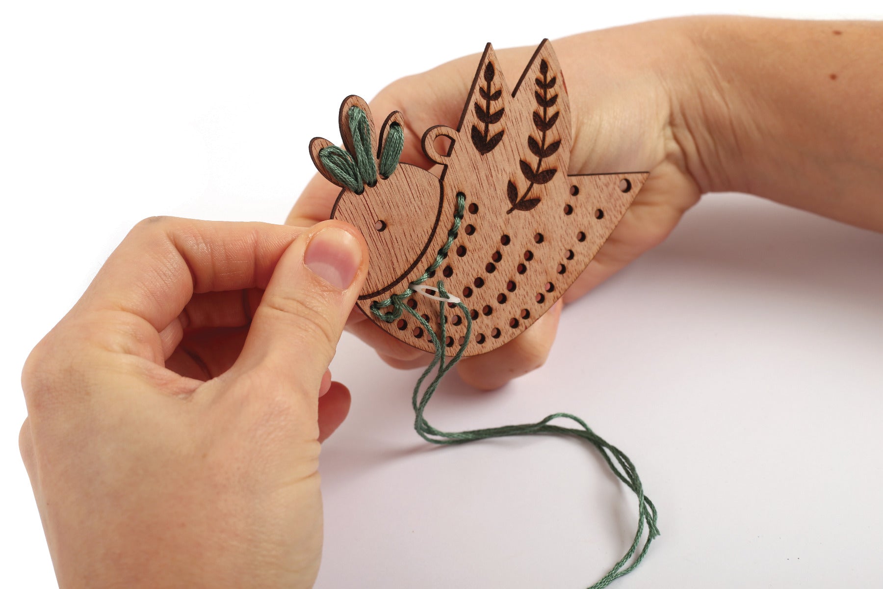 Jemand bestickt das Holz Vogel Tannenbaum Schmuckstück mit grünem Garn