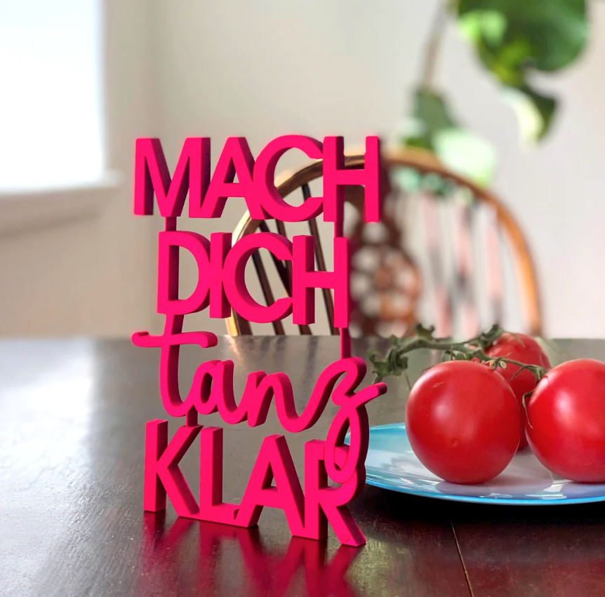 Wanddekoration aus Holz gefärbt in Neon Pink in Form einer Schrift "Mach dich tanz klar"