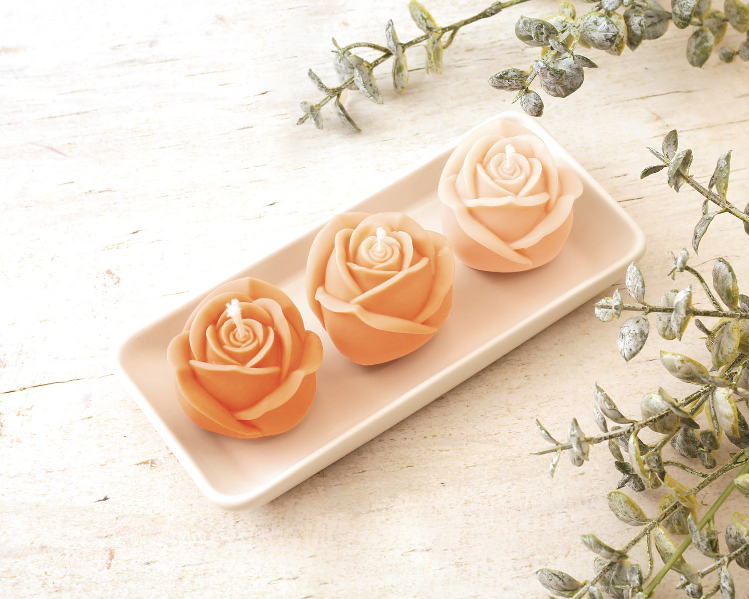 Die drei fertigen Rosen Kerzen auf dem Kerzenteller auf einem TIsch mit Dekoration