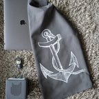 Graues Baumwoll-Geschirrtuch mit einem weißen Anker-Aufdruck hängt in der Küche mit Deko