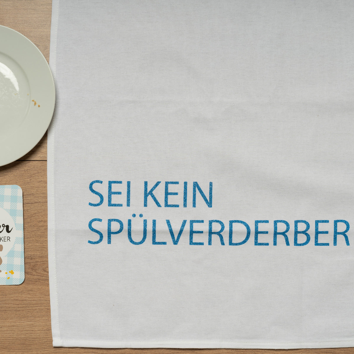 Das Baumwoll Geschirrtuch liegt auf einem Holztisch 