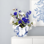 Die Faltvase mit einem Delfter Blau Design in Blau/Weiß, auf einem Tisch mit bluen Blumen 