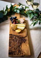 Ein Eichen Servierbrett mit einem eingebranntem "Hochlandrind" Design mit zwei Weingläsern und Dekor