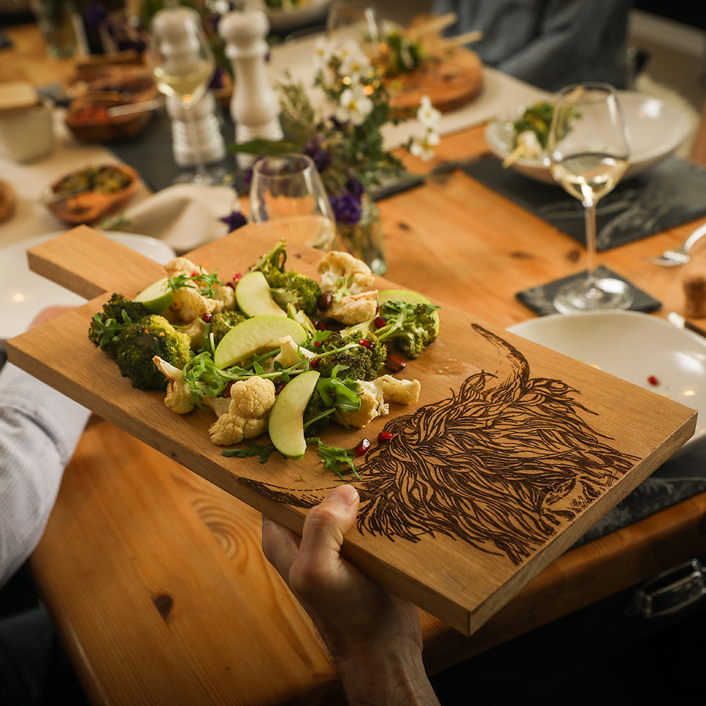 Jemand Serviert Salat auf dem Eichen Servierbrett mit eingebrannten Hochlandrind Muster