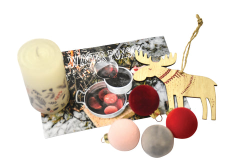 Eine Kerze mit verschidenen Winter-Sträucher Muster, eine Postkarte mit der Aufschrift "Winter Punsch" und abgebildetem Punsch, sowie vier Weihnachtskugeln und einem hölzernen Hirsch ebenfalls mit Bändchen zum aufhängen