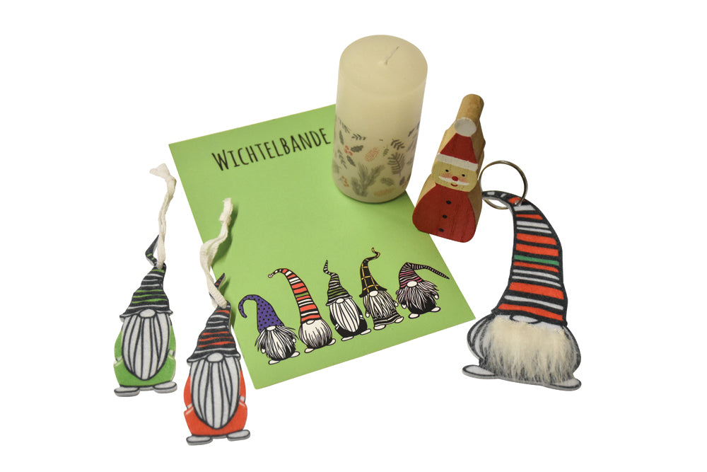 Eine Postkarte mit Wichtel Motiv auf der "Wichtelbande" steht, drei Filz-Wichtel für den Tannenbaum und einem Holzfigur-Wichtel und einer Weihnachtlichen Kerze