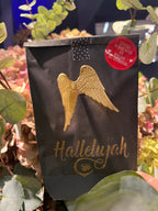 Schwarze Wundertüte mit einer Goldenen Schrift "Hallelujah" und aufgeklebten goldenen Flügeln