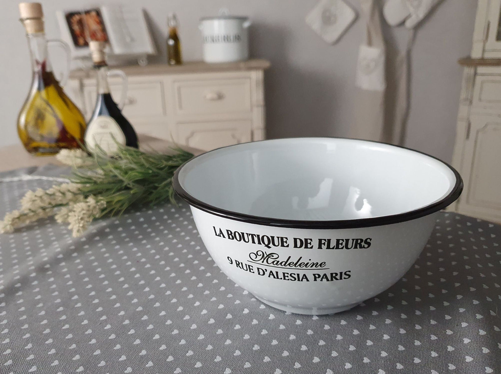 Weiße Schüssel mit der schwarzen Schrift "La Boutique De Fleurs" auf einem Tisch 