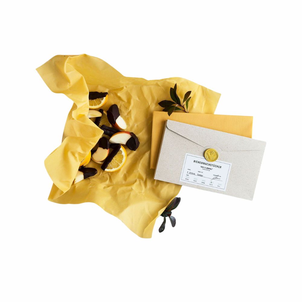 Ein Bienenwachstuch in Gelb umgeben von Vaillie und Zitronen