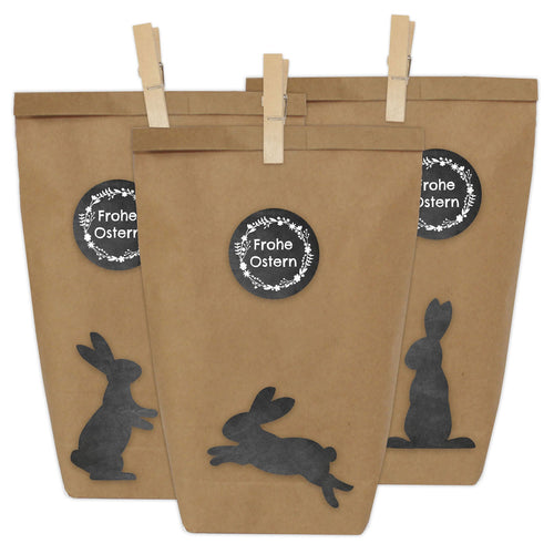 Drei braune Wundertüten mit einem Aufkleber auf dem steht "Frohe Ostern" mit drei verschiedenen Hasen Muster in Schwarz
