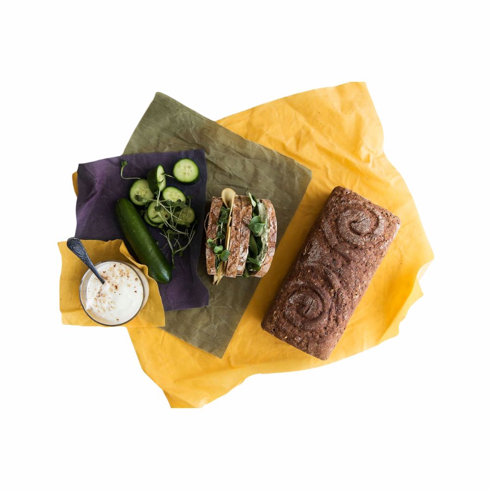 Auf den Bienenwachs-Tüchern liegen Brot, ein Sandwich und eine Gurke