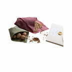 Nachhaltiges rotes Bienenwachstuch, zu einer Tasche gefaltet, mit Walnüssen und Pflanzensamen gefüllt