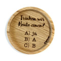 Eingekerbter Holzuntersetzer mit dem aufgedruckten Spruch „Trinken wir Heute einen?- A) Ja B) A C) B"