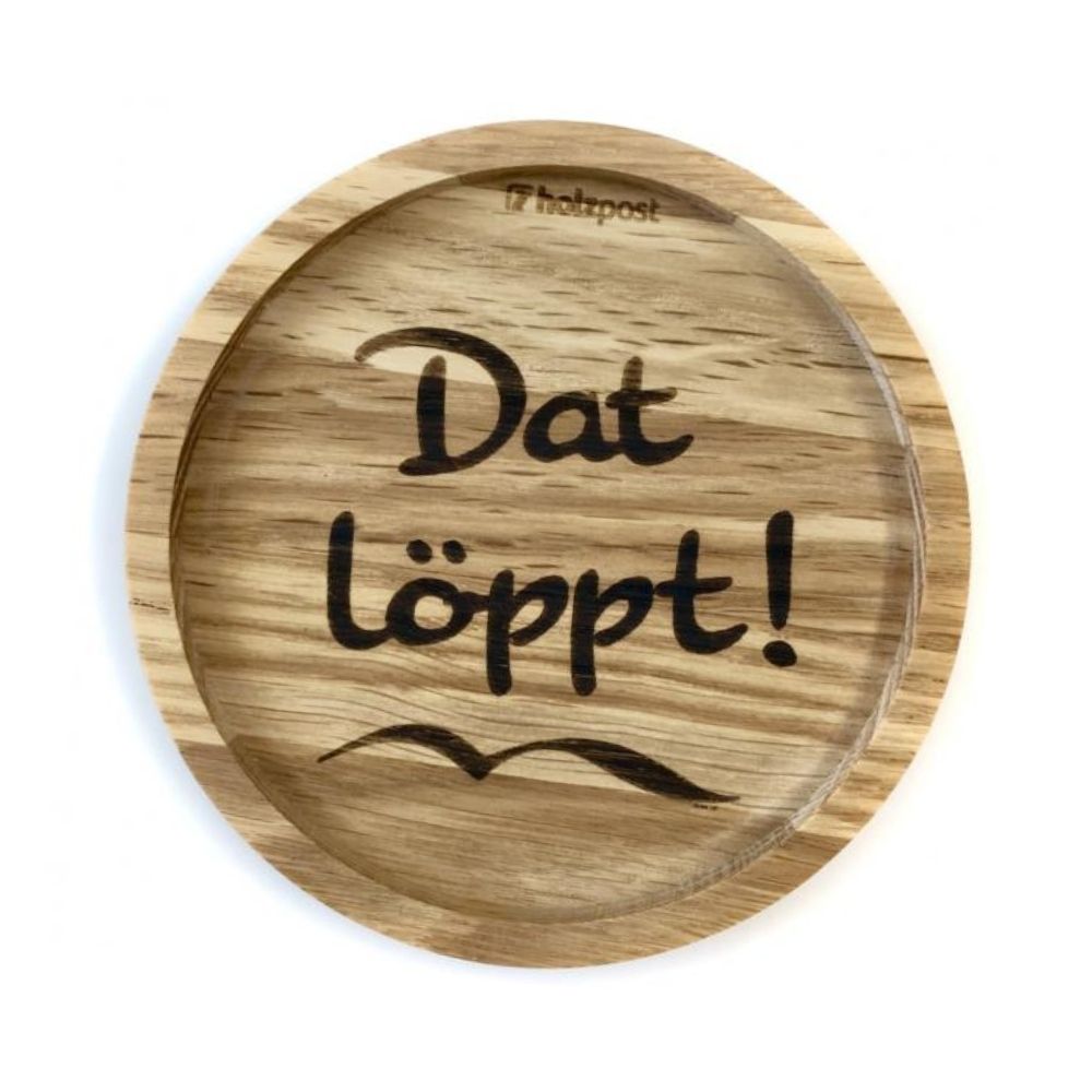 Eingekerbter Holzuntersetzer mit dem aufgedruckten Spruch „Dat löppt!" und einer Seemöwe