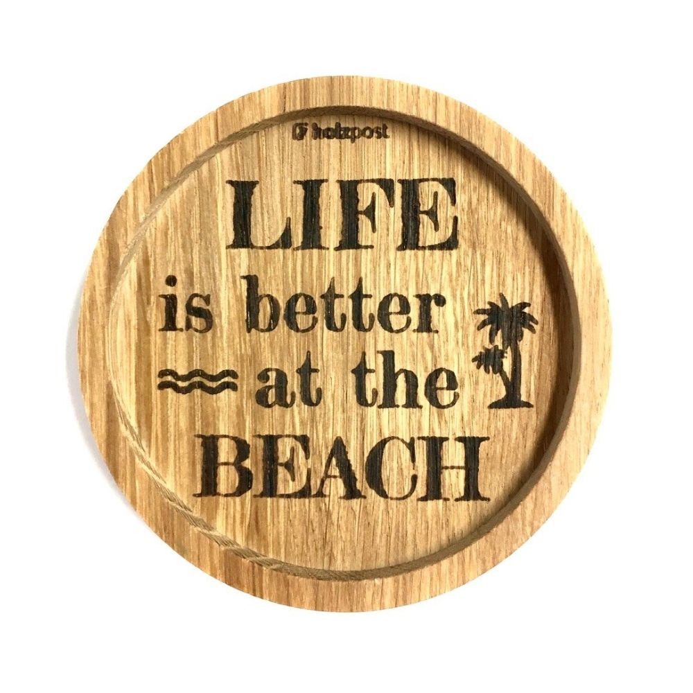 Eingekerbter Holzuntersetzer mit dem aufgedruckten Spruch „LIFE is better at the BEACH"