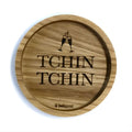 Eingekerbter Holzuntersetzer mit dem aufgedruckten Spruch „TCHIN TCHIN" und zwei kleinen Sekt-Gläsern