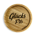 Eingekerbter Holzuntersetzer mit dem aufgedruckten Spruch „Glücks Pils"