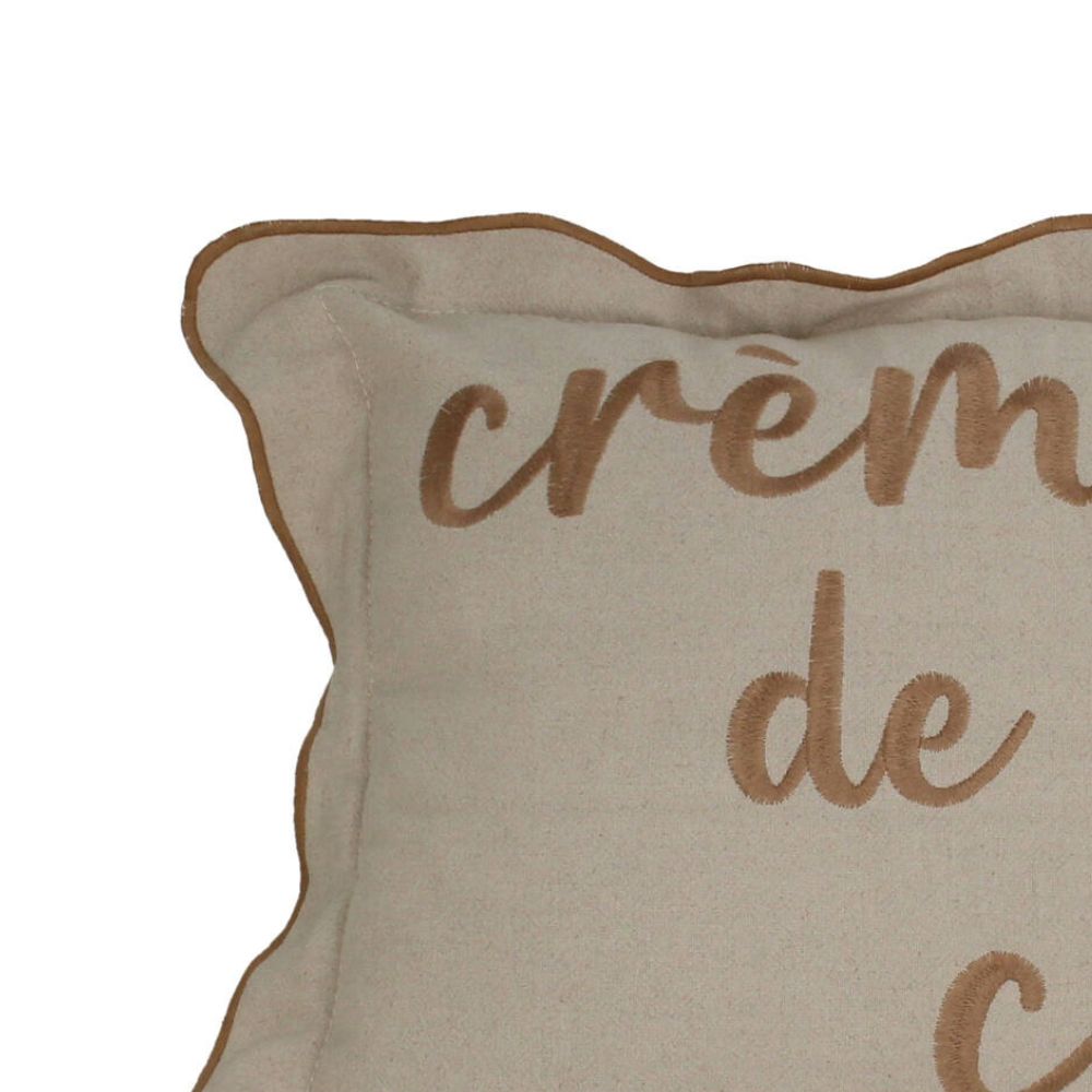 Nahaufnahme von Sofakissen aus Baumwolle, Beiger Kissenbezug mit leicht gerüschtem hellbraunem Saum und hellbrauner kursiver Aufschrift "Créme de la Créme", 30 x 50 cm großes Kissen 