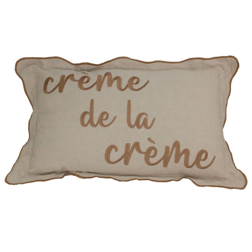 Beiges Kissen aus Baumwolle mit hellbrauner kursiver Aufschrift "Créme de la Créme", leicht gerüschter sauber vernähter Rand, 30 x 50 cm