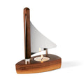 Teelichthalter in Form eines Segelbootes, Boot aus dunklem Walnussholz, Segel aus hochglanzpoliertem Edelstahl, "Im Boot" ist eine Vertiefung in dem ein Teelicht herkömmlicher Größe Platz findet