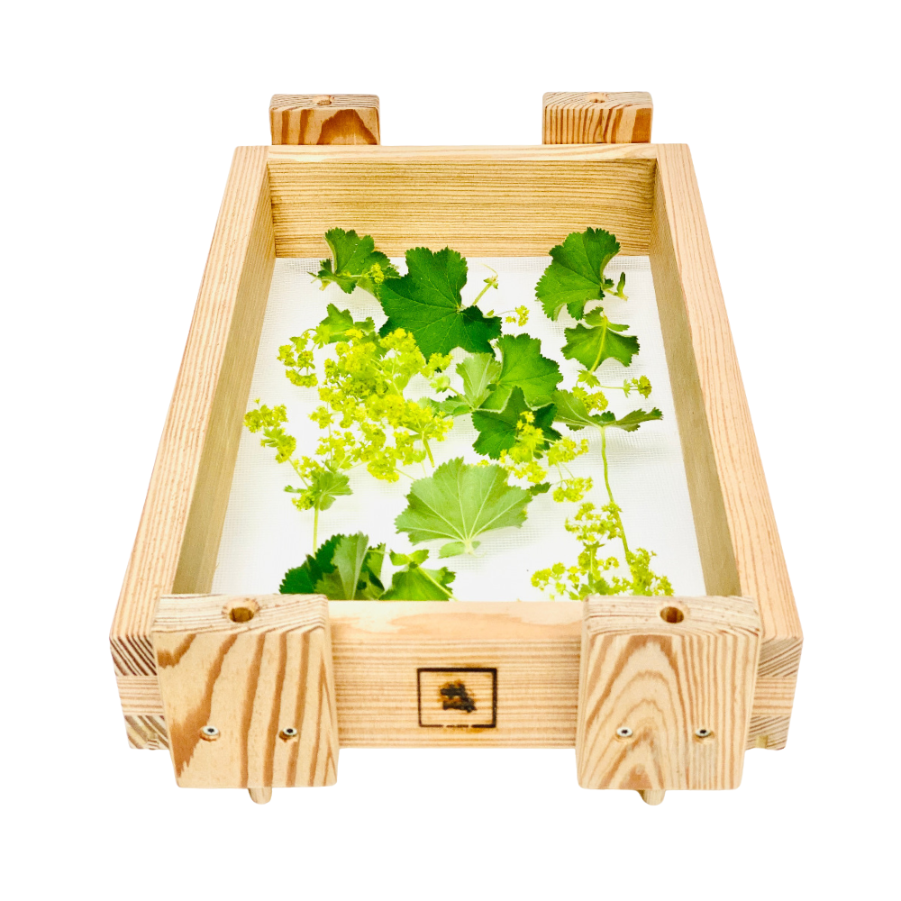 Ein Kräutertrockner, der aus einem Holzrahmen besteht und Füße für die Luftzirkulation hat. Im Rahmen ist ein Netz gespannt auf dem verschiedene Kräuter trocknen