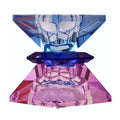 Ein hoher wendbarer Kerzenhalter aus Glas in Violett, Braun und Kobalt Kristall-Optik, bestehend aus mehreren geometrischen Flächen. Der Kerzenhalter hat eine moderne, facettierte Optik, die das Licht reflektiert