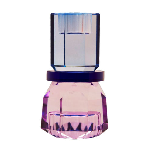 Ein kleiner wendbarer Kerzenhalter aus Glas in Violett, Blau und Kobalt Kristall-Optik, bestehend aus mehreren geometrischen Flächen. Der Kerzenhalter hat eine moderne, facettierte Optik, die das Licht reflektiert.