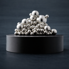 200 unterschiedliche große silberne glänzende Stahlkugeln auf einem Magnet sockel. Oval geformerter matter schwarzer Magnetsockel. Angerichtet vor dunkelblauem schlichtem Hintergund