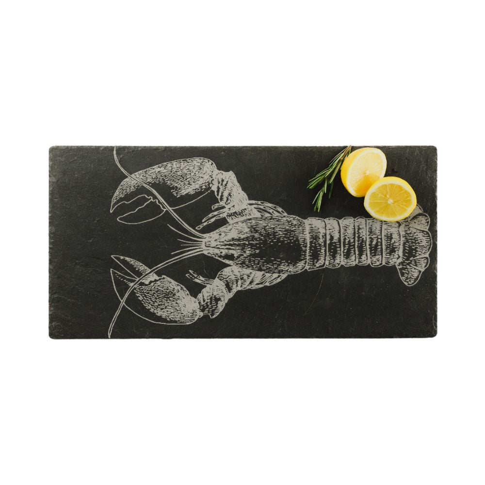 Eine rechteckige Servierplatte aus Schiefer mit einem eingravierten Hummer-Motiv und zwei Zitronen hälften, die auf der Platte liegen