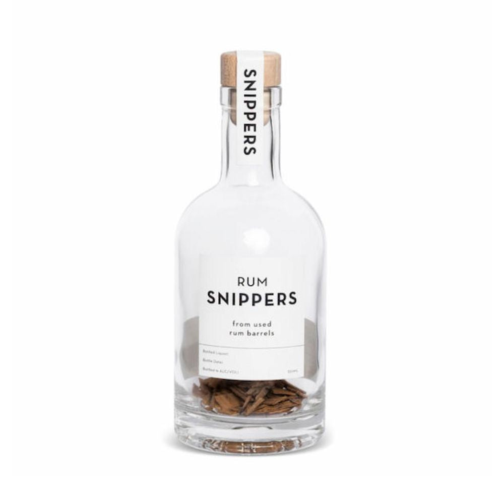 Eine mit Holzschnipsel von alten schottischen Fässern -  Leere Rum-Flasche mit Kork-Verschluss mit der Aufschrift "Rum Snippers Deluxe" und die kleinere Version "Rum SNIPPERS" daneben von Rum Amsterdam