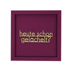 Quadratische Wanddekoration in Aubergine mit dem Spruch "Heute schon gelächelt?"