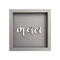 Quadratischer Papp-Bilderrahmen in Dunkelgrau mit der Schrift "Merci"
