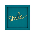Quadratische Wanddekoration in Petrol mit der Gelben Schrift "Smile"