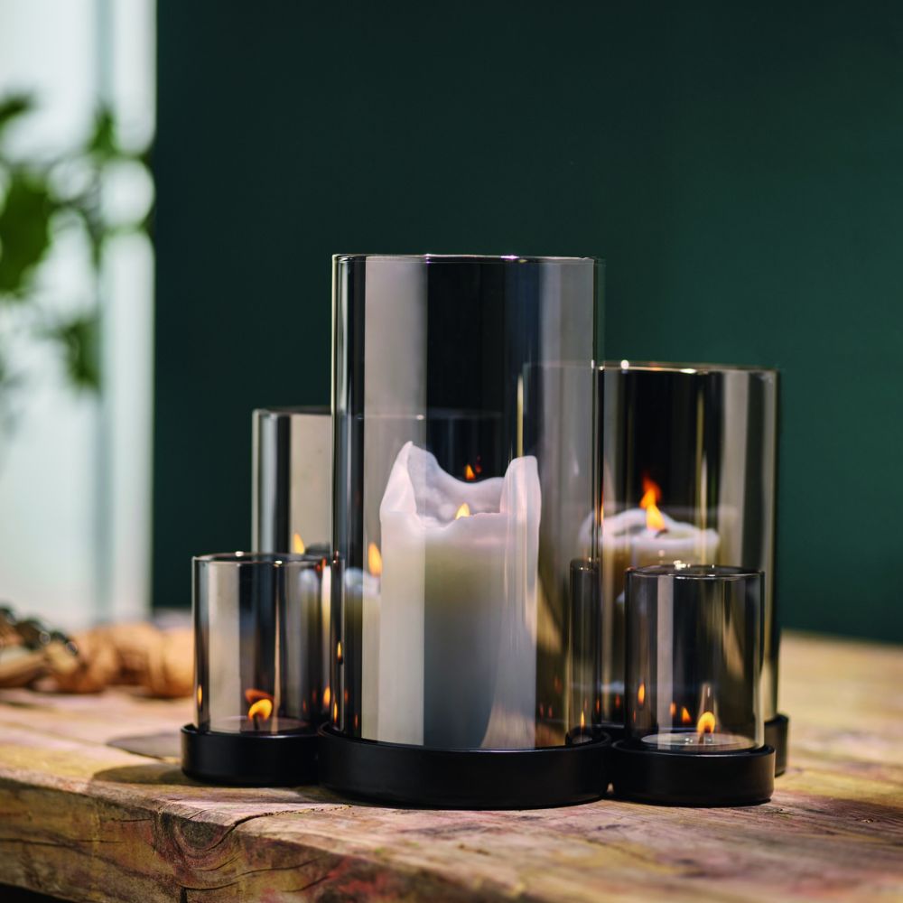 Schönes Windlicht mit 6 verdunkelten verschieden hohen Glasrohren für 6 Teelichter, angerichtet in schönem Setting auf einem natürlichem Holz Tisch