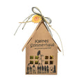 Braune Papierbox in Form eines Hauses mit der Schrift "Kleines Sommerhaus mit Sonnenblumenfeld". Zusätzlich sind Gartenutensilien und ein Gartenzwerg aufgedruckt