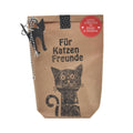 Braune Wundertüte mit schwarzer Schrift „Für Katzenfreunde“ und dem Aufdruck einer fröhlichen Katze. Oben links ist ein Filzplättchen in Katzenform befestigt