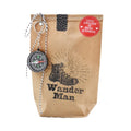 Braune Wundertüte mit einem schwarzen Aufdruck von einem Wanderstiefel und der Schrift "Wander Man", Oben links ist ein Kompass and einer Kette befestigt
