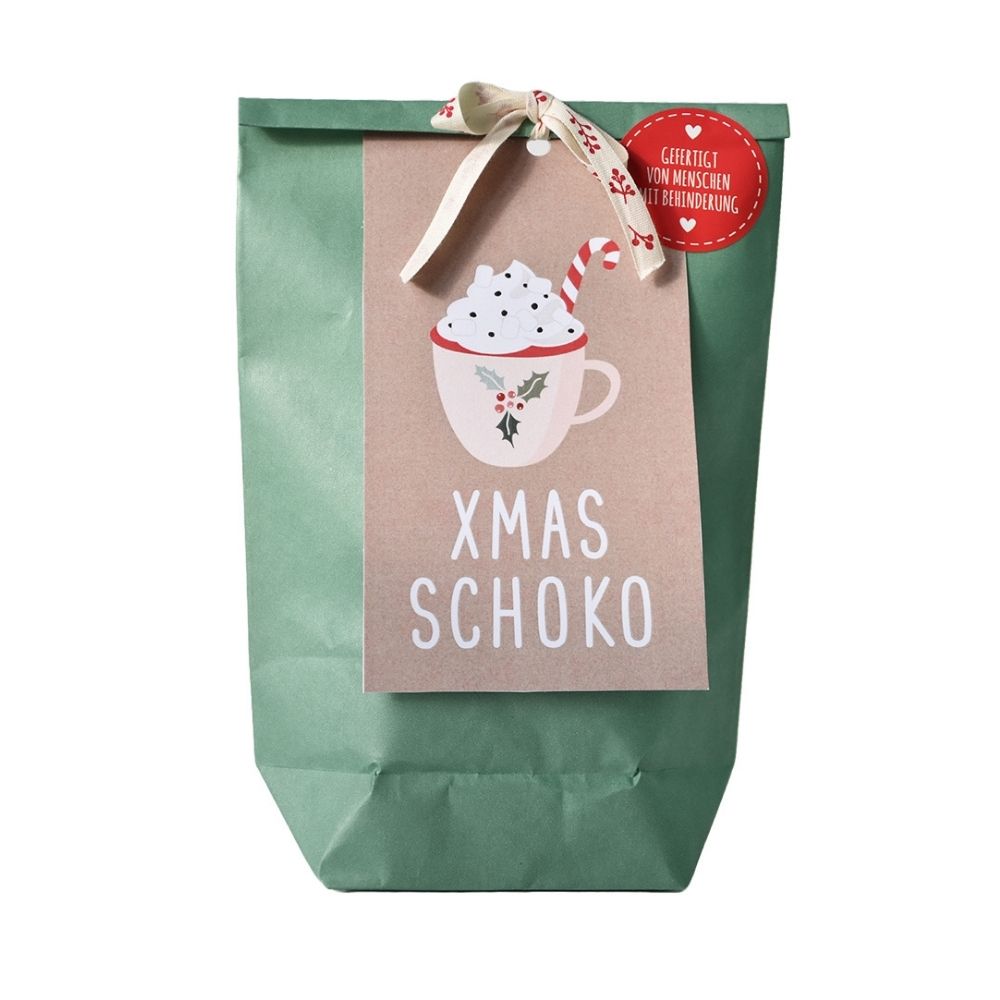 Grüne Wundertüte mit einer angebundenen braunen Karte auf der eine Weihnachtliche Tasse abgebildet ist auf der Karte steht "XMAS SCHOKO"