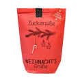 Rote Wundertüte mit einem aufgedruckten Tannenzweig an dem eine kleine Zuckerstange hängt mit der Schawrzen Schrift "Zuckersüße Weihnnachtsgrüße"