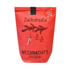 Rote Wundertüte mit einem aufgedruckten Tannenzweig an dem eine kleine Zuckerstange hängt mit der Schawrzen Schrift "Zuckersüße Weihnnachtsgrüße"