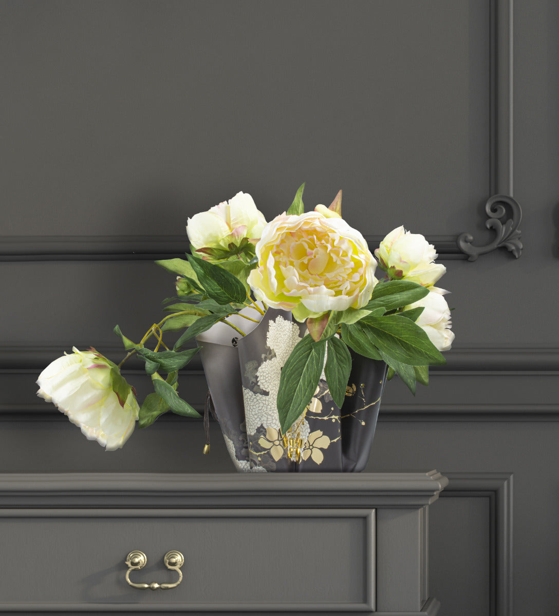 Faltvase mit Schwarz, Gold Blumen Design, innenseite grau gefärbt, zusammengehalten mit einem schwarzen Band auf einem Tisch mit Blumen innendrin