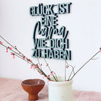 Wanddekoration grüner Schriftzug "Glück ist eine mama wie dich zu haben" an der Wand im Wohnzimmer