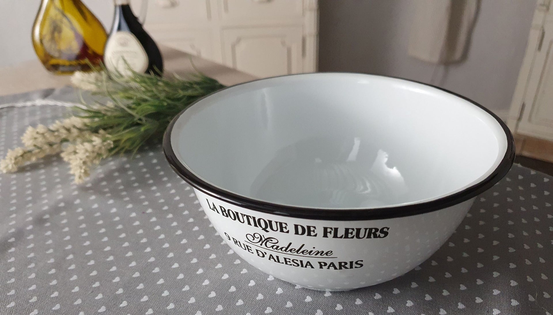 Weiße Schüssel mit der schwarzen Schrift "La Boutique De Fleurs" auf einem Tisch, andere Perspektive