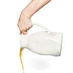 Hand gießt Schwarz-Tee aus der Weißen Designer Keramik Karaffe mit unebenen Flächen mit dutchdeluxes Logo