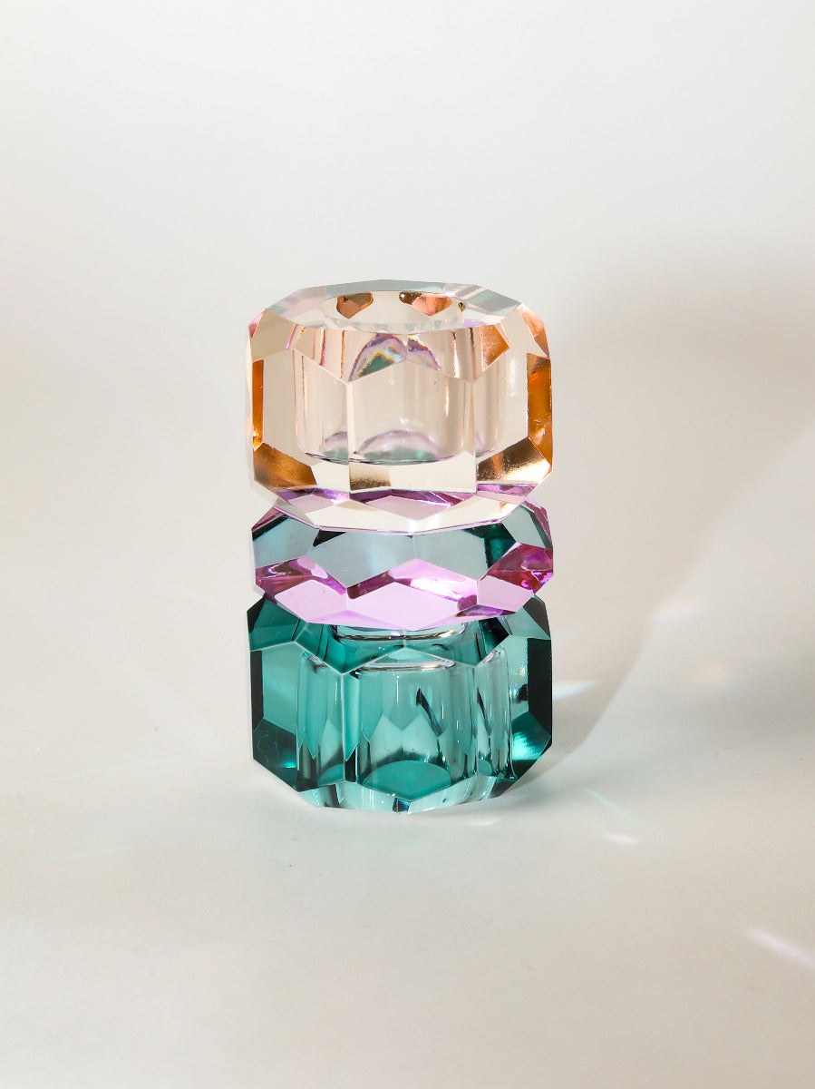 Ein hoher wendbarer Dioptrics Kerzenhalter aus Glas in Petrol, Violett und Pfirsich Kristall-Optik, bestehend aus mehreren geometrischen Flächen. Der Kerzenhalter hat eine moderne, facettierte Optik, die das Licht reflektiert